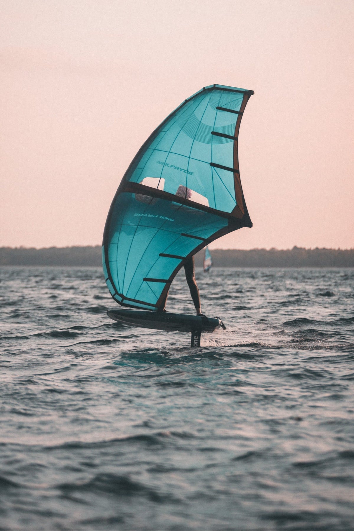 Ein Wingfoil-Student fliegt auf einem Tragflügelboot über das Wasser.